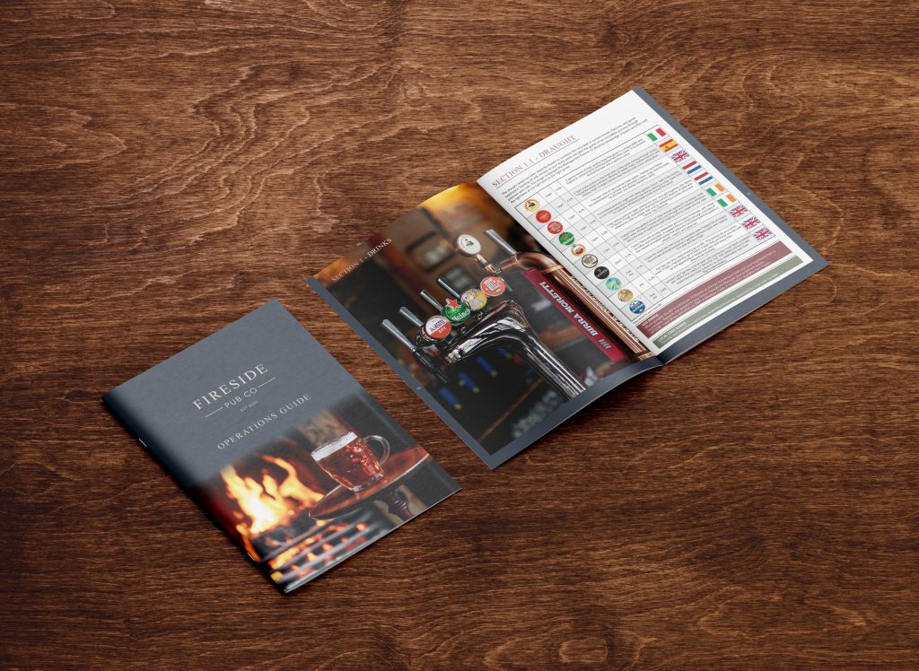 Fireside restaurant operational guide, opened on a wooden surface, showcasing bar and drink images, designed through our hospitality artwork services.